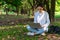 Young caacasian businesswoman sitting under tree in natural park using laptop computer for work outside office