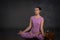 Young calm beautiful woman of the brunette with long hair wearing lilac overalls in yoga pose