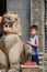 Young Cambodian boy waiting outside a temple with statue