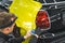 young car specialist applying neon yellow vehicle vinyl wrap onto the surface of a black car