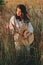 Young carefree female in rustic linen cloth posing in summer meadow. Summer delight and travel. Stylish boho woman with straw hat