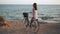 Young carefree happy woman with bicycle looking away smiling standing on yellow beach at Mediterranean sea on Cyprus