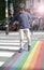 Young careful child walking through the rainbow crosswalk, halo effect