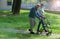 A young caregiver accompanies an elderly gentleman helping him to walk in the park