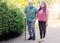 A young caregiver accompanies an elderly gentleman helping him to walk in the park