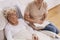 Young carer reads a book to an elderly woman lying in a hospital bed