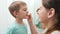 Young caring mother brushing and cleaning teeth of her little son. Parents and children taking care of teeth health and