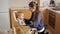 Young caring mother seating her baby son in highchair to feed him on kitchen