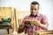 Young carpenter african american man looking and choosing wood and using sandpaper to rub wooden plank at workshop table in