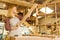 Young carpenter lady examining wooden piece after grinding