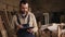 Young carpenter walking through the workshop with tablet in hands. Workshop with timber and equipment stuff on the