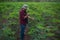 Young cassava farmer uses a smartphone to take pictures of cassava leaves to analyze their growth