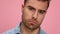 young casual man in blue shirt posing on pink background