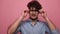 Young casual man with glasses on pink background