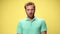 young casual man in green polo shirt on yellow background