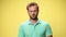 young casual man in green polo shirt on yellow background