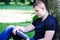 Young casual man sitting on the ground and leaning to a tree