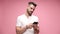 young casual man in white shirt posing on pink background