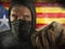 Young Catalan man as ultra and radical separatist holding brick protesting in face mask holding brick threatening at nationalistic