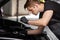 Young caucasian auto mechanic in a car service, checks a car, engine, carburetor