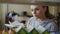 Young caucasian beautiful female student is standing near shelf with books in big spacious library holding one, turning