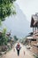 Young Caucasian blonde woman with backpack walking on the central street of Muang Ngoi village, Laos