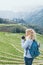 Young Caucasian blonde woman in denim shirt taking pictures of Sapa rice terraces at sunset in Lao Cai province, Vietnam