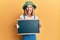 Young caucasian blonde woman holding blackboard sticking tongue out happy with funny expression