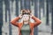 Young Caucasian blonde woman puts on her autumn wreath standing in the pine forest