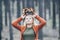 Young Caucasian blonde woman puts on her autumn wreath standing in the pine forest