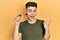 Young caucasian boy with ears dilation holding sdxc card pointing thumb up to the side smiling happy with open mouth