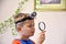 Young Caucasian boy with head torch lamp looking through a magnifier glass