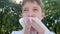 A young caucasian boy sitting in summer city park and wiping his mouse, lips with paper napkin, towel after eating, close up view