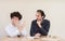 Young Caucasian businessman cocking a snook at his colleague in office with light background.