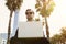 Young caucasian businessman in formal clothes working at sunny day on green grass on laptop. Blurred background.Cropped.