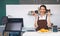 Young caucasian coffee shop staff  dressed in brown apron holding coffee drink in plastic cup with both hands. Morning atmosphere