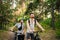 Young caucasian couple of cyclists walk and push their mountain bikes along the forest road in the park. Active sports weekend.