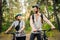 Young caucasian couple of cyclists walk and push their mountain bikes along the forest road in the park. Active sports weekend.