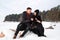 Young caucasian couple in love sitting on stone with dog on winter beach, embracing, enjoy the romantic moment, feeling intimacy