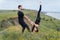 Young caucasian couple practicing acro yoga together on the hill near the sea. Couple, partner yoga. Athlete flexing beautifully