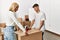 Young caucasian couple smiling happy closing box using packing tape at new home