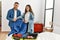 Young caucasian couple smiling happy unpacking suitcase at home