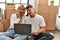 Young caucasian couple surprised using laptop sitting at new home