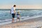 Young Caucasian dad with little son walk warm summer day along the sea coast. Summer family vacation concept. Friendship father