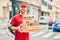 Young caucasian deliveryman smiling happy holding delivery food at the city