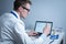 Young caucasian doctor working at table in hospital laboratory examining an ampoule of medicine and entering data into