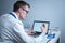 Young caucasian doctor working at table in hospital laboratory examining an ampoule of medicine and entering data into