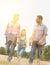 Young Caucasian family walking across field with young girl holding bouquet of flowers, concept organic ecologically friendly fami