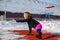 Young caucasian female blonde in violet leggings stretching exercise on a red running track in a snowy stadium. fit and sports