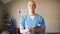 Young Caucasian female doctor in scrubs removing stethoscope and folding arms